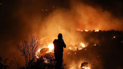A man uses his mobile phone as wildfires burn a forest in Chbaniyeh village, Lebanon. Reuters