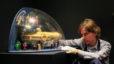 A Sotheby's employee poses with a "The Empire Strikes Back" Toy figures and a Millenium Falcon toy shop display from 1980, estimated at £7,000-£10,000, during a photocall at Sotheby's in London. Reuters