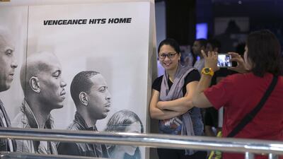 People pose for pictures with a Furious 7 poster before they enter the cinema to view the first showing of the movie in Abu Dhabi, at Vox Cinema in Marina Mall. Silvia Razgova / The National