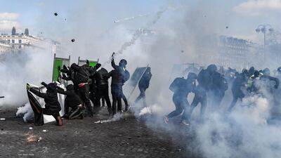 Yellow Vest protesters take shelter behind fences during clashes with riot police forces on the Champs-Elysees in Paris. AFP