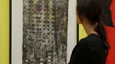 A woman poses for photographs in front of "Five Grand" by artist Luke Wade which shows the burnt out Grenfell Tower and features in this year's Summer Exhibition on it's 250th year at the Royal Academy of Arts in London. Matt Dunham / AP photo