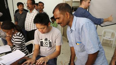 Jaiprakash Chauhan, right, from Uttar Pradesh, India, selects his portrait photo taken by Gulf Photo Plus Gallery at Al Quoz Industrial Area in Dubai. Pawan Singh / The National