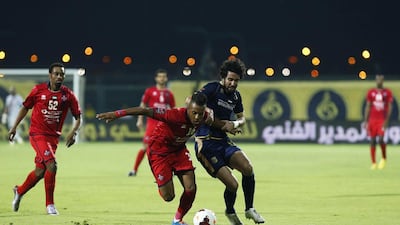 Michael N'dri, centre, of Al Shaab fights his way past Saleh Saidi of Dubai during their Arabian Gulf League match in Dubai on April 27, 2014. Antonie Robertson / The National