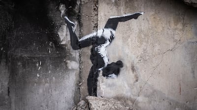 A Banksy artwork of a woman in a leotard doing a handstand is seen on the wall of a destroyed building in Borodyanka. Getty.