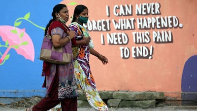 Women walk in front of a graffiti painted on a roadside wall in Bangalore, India. EPA