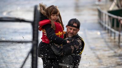 A volunteer carries a young girl to safety after she was stranded by rising water in Abbotsford.