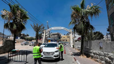 Palestinian volunteers check the temperature of a people in a car at the entrance of the Amari refugee camp near the West Bank city of Ramallah. AFP