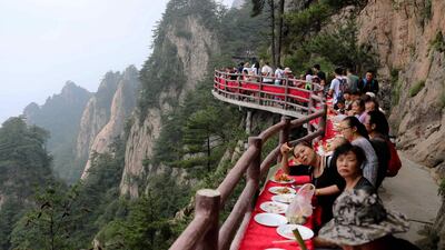 Food lovers enjoy a banquet held along the edge of a cliff, at Laojun Mountain in Luoyang in China's central Henan province. The banquet was held on a mountain cliff 2,000m (6,500ft) above sea level to attract tourists. AFP