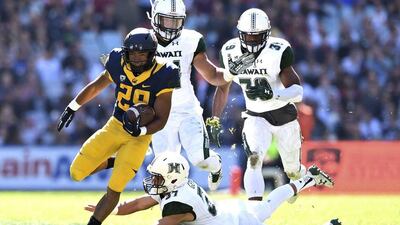Khalfani Muhammad, left, of the California Golden Bears beats a tackle by Austin Gerard, centre, of the Hawaii Rainbow Warriors. Paul Miller / EPA