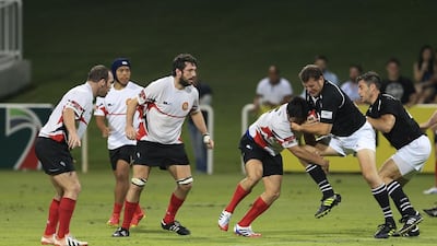 UAE rugby player Daniel Minks pushes against a Singapore tackler during Wednesday night’s Asian Five Nations Test. Sarah Dea / The National / April 23, 2014