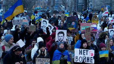 People hold portraits of Ukrainian President Volodymyr Zelenskyy and other banners during an anti-war rally in front of the Palace of Culture and Science in Warsaw, Poland. AP