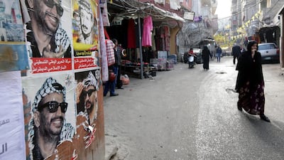 A picture taken on December 21, 2017 shows posters of late Palestinian leader Yasser Arafat plastered on a wall as residents walk past them down a street in the Burj Al Barajneh camp, a southern suburb of the Lebanese capital Beirut. ANWAR AMRO / AFP