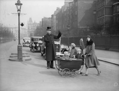A top-hatted gentleman escorts a lady and her charges across the road to St James's Park, at Birdcage Walk, London in 1934. Getty Images
