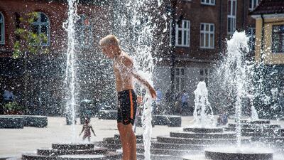 A boy enjoys a bath in the fountain at Toldbod Plads in Aalborg, Denmark, while the thermometer shows 30 degrees Celsius. EPA