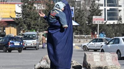 A woman carrying a child begs for alms on a street in Kabul, Afghanistan. In low and middle-income countries, surging Covid cases strained healthcare systems during the pandemic. AFP