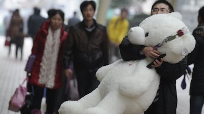 A man carries a large teddy bear and a rose on a street in Shanghai on February 14, 2012. Valentine's Day is a holiday observed on February 14 honouring one or more early Christian martyrs named Saint Valentine. AFP PHOTO/Peter PARKS