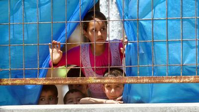Syrian refugee children look through a fence at a refugee camp in the Turkish border town AFP