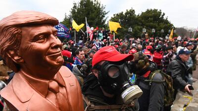A supporter of Donald Trump wears a gas mask and holds a bust of him after he and hundreds of others stormed stormed the Capitol building on January 6, 2021 in Washington AFP