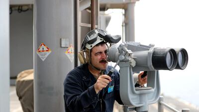 A US Navy officer uses binoculars to follow the movements near the USS Boxer.