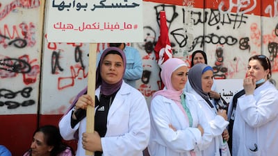 A healthcare worker holds a placard reading "Hospitals will close their doors, we cannot continue this way" during a protest against banks restricting cash dealings for hospitals, in front of Lebanon's Central Bank building in Beirut on May 26, 2022. Reuters