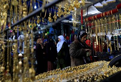 Women walk in front of shops selling golden jewelry at a market street in the northeastern Syrian town of Qamishli. Delil souleiman / AFP