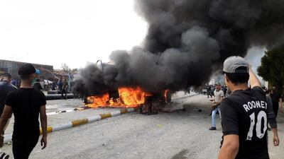 Iraqi protesters gather as smoke rises from a burning military truck after clashes between protesters and Iraqi policemen in Nasiriyah city, some 370km southeast of Baghdad, Iraq. EPA