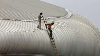Workers climb down the roof of the weightlifting venue for the Commonwealth Games in New Delhi where a portion of false ceiling has collapsed.