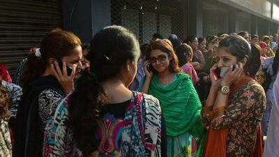 Pakistani office workers in Karachi speak on their mobile phones after being evacuated after a 7.8-magnitude earthquake hit southwestern Pakistan today. Rizwan Tabassum / AFP Photo