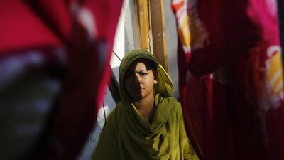 Khodeja, 25, who was rescued from the rubble of the collapsed Rana Plaza building, stands in front of her slum house in Savar. Khodeja who is unable to work due to a spinal injury sustained from the accident last year.