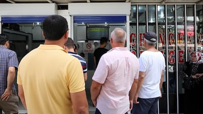 People look at foreign exchange rates in Ankara, Turkey, on August 10, 2018. - Turkish President Recep Tayyip Erdogan called on Turks to support their struggling currency, the lira, by exchanging any foreign money, saying Turkey faces an economic war. (Photo by ADEM ALTAN / AFP)