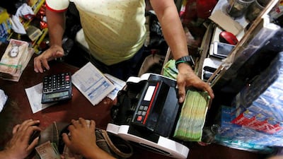 A man uses a machine to count Venezuelan bolivar notes at a store in Puerto Santander. Inflation has left the currency almost worthless. Carlos Garcia Rawlins/Reuters