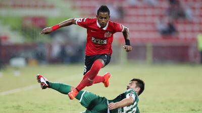 Abdelaziz Haikal, top, of Al Ahli leaps over a tackle from Carlos Villanueva of Al Shabab during their Arabian Gulf League match at Rashid Stadium in Dubai on September 21, 2014. Ashraf Al Amra / Al Ittihad