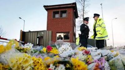 Police Service of Northern Ireland officers talk beside flowers laid on the ground during a security patrol outside Massereene British Army Base, Antrim, Northern Ireland, today.