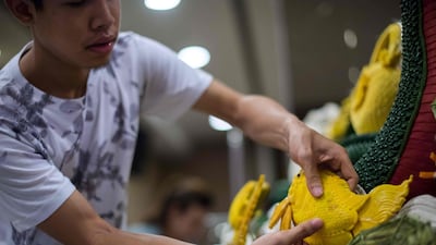 A man adds a pumpkin carved in the shape of a fish to an elaborate display during a fruit and vegetable carving competition in Bangkok. Robert Schmidt / AFP