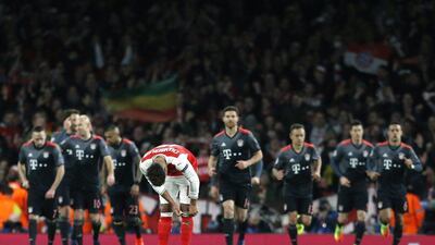 Bayern Munich players jog back after scoring their second goal as Alex Oxlade-Chamberlain adjusts his socks. Ian Kington / AFP