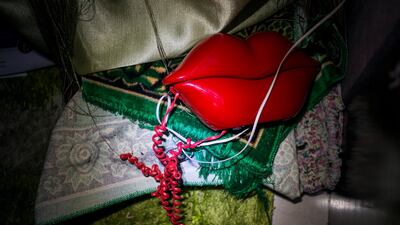 A phone shaped like lips and a prayer rug sit in the corner during a blackout.