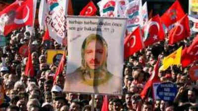 A demonstrator in Ankara holds a poster of Recep Tayyip Erdogan, the Turkish prime minister, wearing a headscarf under the slogan, "You insist on the headscarf, let's see you wear it first! "