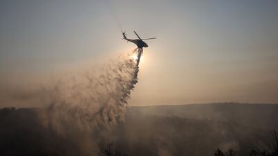 A firefighting helicopter drops water to extinguish a fire in the Souni area near Limassol. Reuters