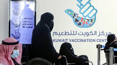 A woman pushes another in a wheelchair as they queue to register before receiving a dose of Covid-19 coronavirus vaccine at the Kuwait International Fairground on February 1, 2021. AFP