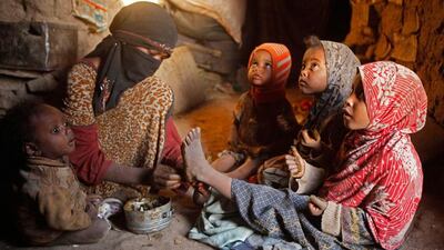 A woman applies traditional Henna dye on the legs of her daughters.