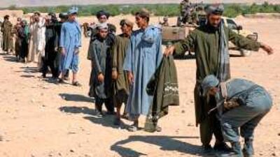 An Afghan policemen searches voters in front of a polling station of Lublan, in southern Afghanistan, on August 20, 2009.