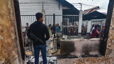 An armed plainclothes policeman (L) secures the around around Siak prison in Siak Sri Indrapura in Riau province on May 11, 2019 after rioting and a fire broke out at the detention centre leading to a prison break. AFP
