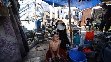 A mother bathes her child in a makeshift shelter at a displacement camp in central Gaza. AFP