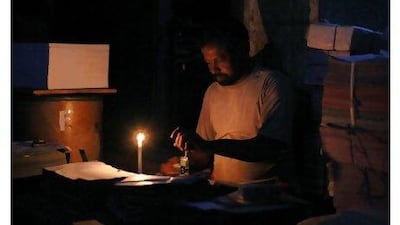 A labourer works by candlelight during a power cut at a printing press shop in Karachi.