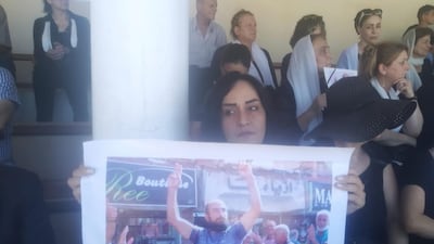 A woman carries a poster of Mr Al Jaramani during his funeral
