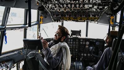 Taliban fighters sit in the cockpit of an Afghan Air Force aircraft at the airport in Kabul on August 31, 2021. AFP