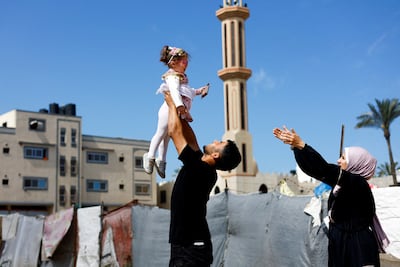 Bisan's uncle holds her aloft, watched by her mother, in Deir Al Balah in central Gaza. Reuters
