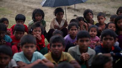 Rohingya refugee children sit in a line in the rain as they wait to receive permission from the Bangladeshi army to continue their way after crossing the Bangladesh-Myanmar border, at a port in Teknaf, Bangladesh on October 31, 2017. Hannah McKay / Reuters