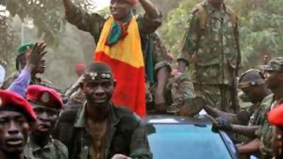 Capt Moussa Camara, centre, the newly self-proclaimed president of Guinea, wears the national flag as he tours Conakry, the capital, the day after a military junta seized power following the death of Lansana Conté, the former president.