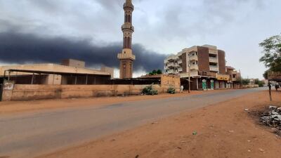 Smoke rises above buildings behind a nearly deserted street in Khartoum on Saturday. AFP